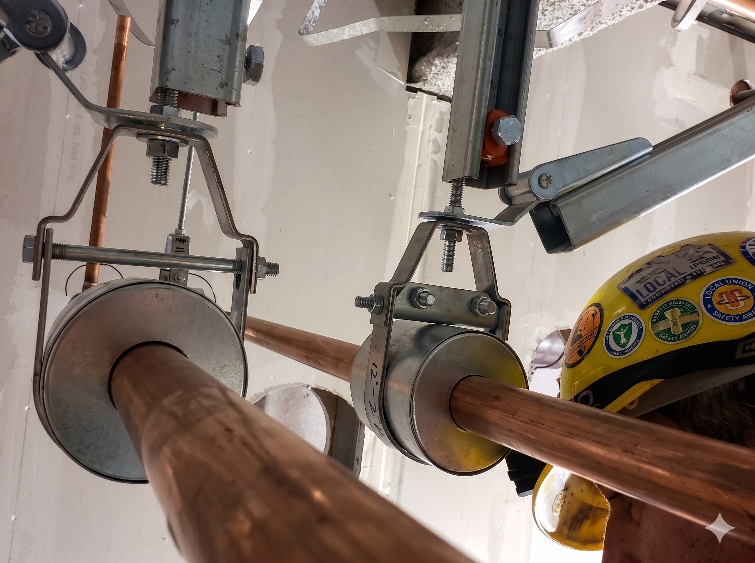 Licensed TrueFlow MD plumber inspecting copper pipe hangers on a commercial install