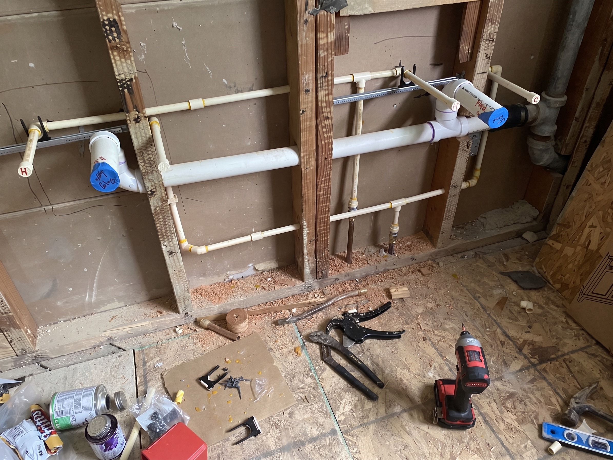 Bathroom rough-in plumbing with PVC supply lines and labeled stub-outs ready for finish work