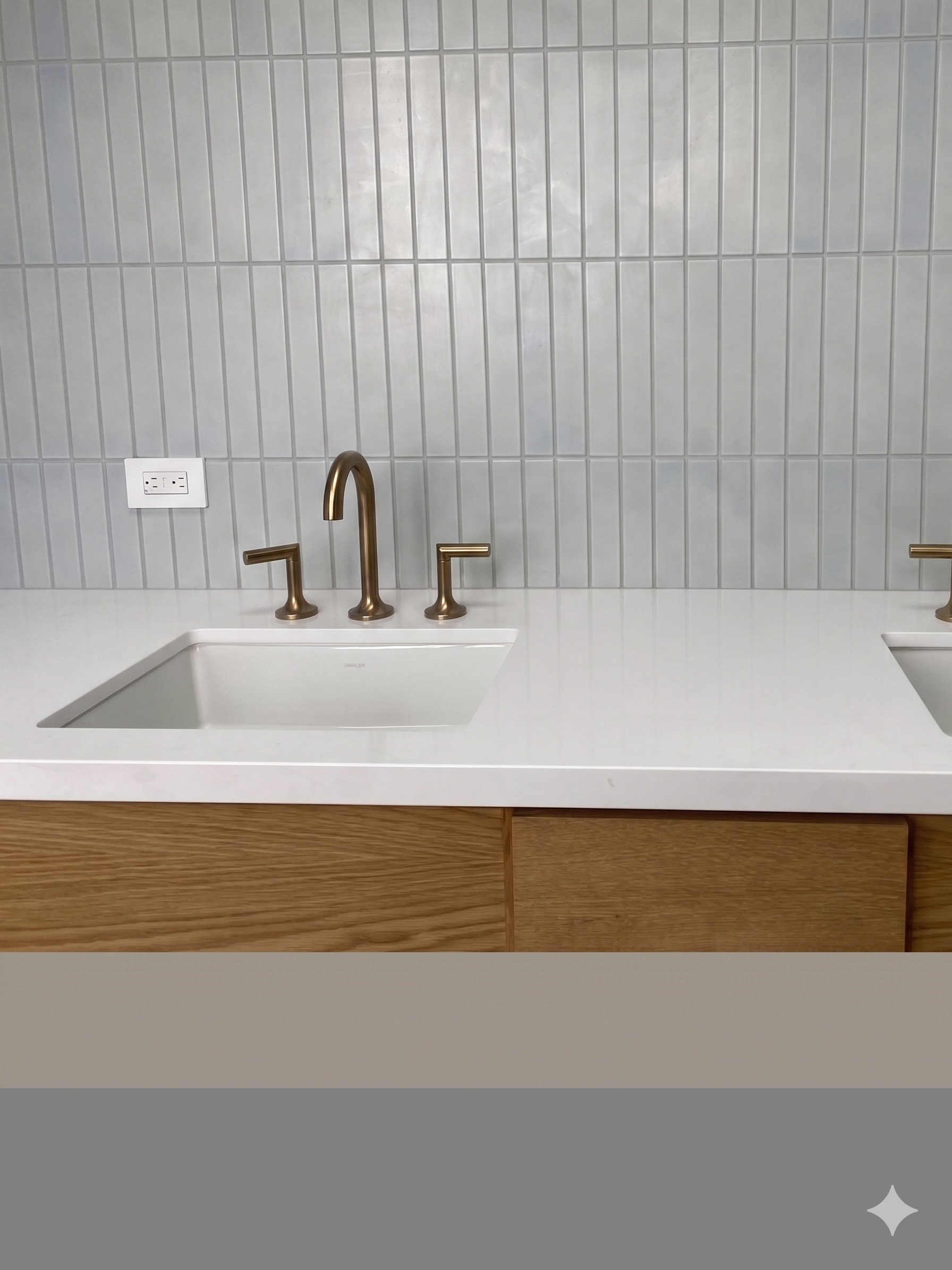Single sink vanity with brass faucet and pale blue vertical-stack tile backsplash